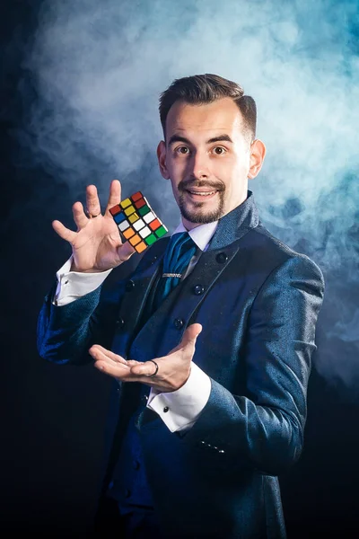 Mavi kuyruklu bir sihirbaz bir rubik küple havalanır.