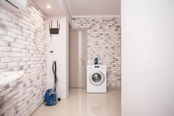 Common area with ironing board, vacuum cleaner and washing machine