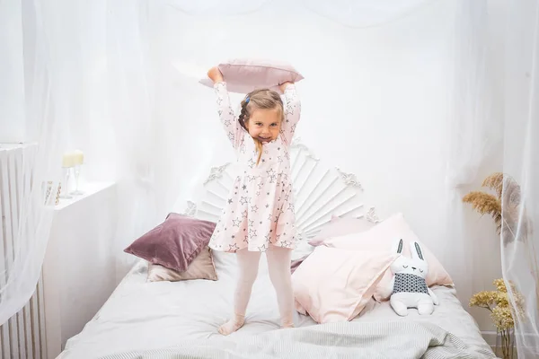 Liten Flicka Rosa Klänning Hoppar Sängen Med Kudde Händerna — Stockfoto