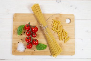 İtalyan makarnası, kiraz domatesleri ve ahşap arka planda fesleğen.