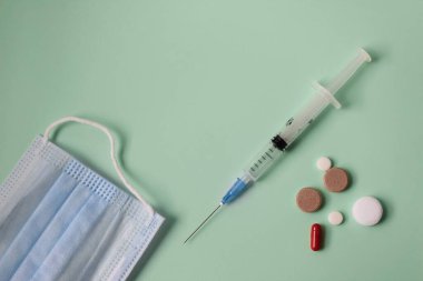 Yeşil arka planda tıbbi düzlük. Haplar, şırınga ve termometre..