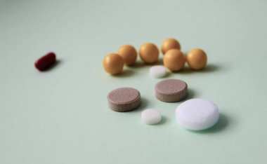 Soyut yeşil bir zemin üzerinde renkli vitamin hapları, ilaç hapları ve kapsüller.. 