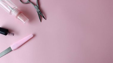 Pembe arka planda maniküre ayarlı. Pembe arka planda tırnak cilası, makas.