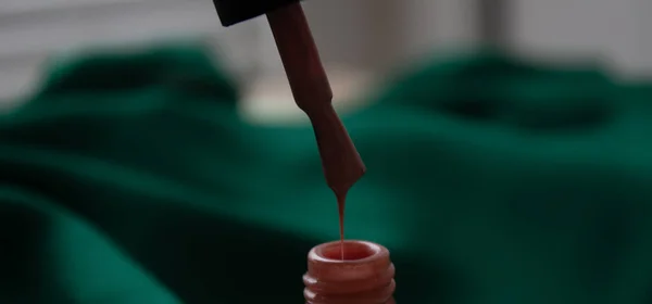 Beyaz bir şişedeki fırçayla birlikte pembe oje. Kalın cila.