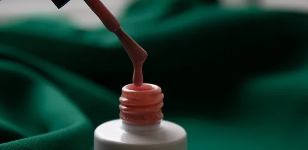 Beyaz bir şişedeki fırçayla birlikte pembe oje. Kalın cila.
