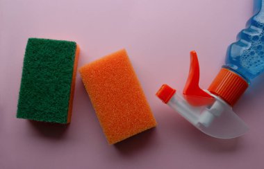 Temizlik için iki portakal ve pembe arka planda mavi temizlik sıvısı..