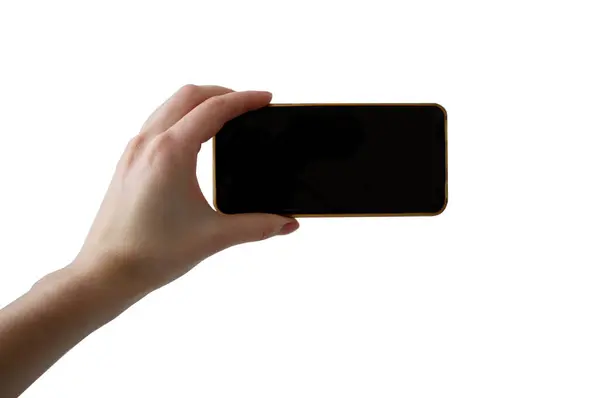 Kadın eli cep telefonunu yatay olarak elinde tutuyor. Kadın ellerinde beyaz arka planda izole edilmiş fotoğraf çekiyor.