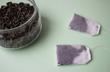 Yeşil arka planda yeşil çay ve poşet çay bırakıyor. Kopyalama Alanı ile Minimalist Düz Yatay.