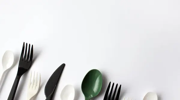 Beyaz arka planda tek kullanımlık plastik çatal bıçak takımı. Mesaj için yer. Çevre sorunu, çevre kirliliği. 