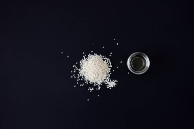 Siyah arka planda taze susam tohumu ve kozmetik susam yağı. Üst görünüm.