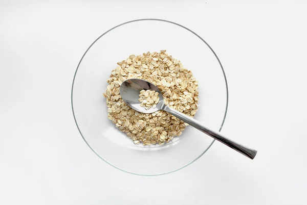 Cereales de avena en un recipiente de vidrio con una cuchara sobre un fondo blanco. Vista desde arriba. Lugar para el texto —  Fotos de Stock