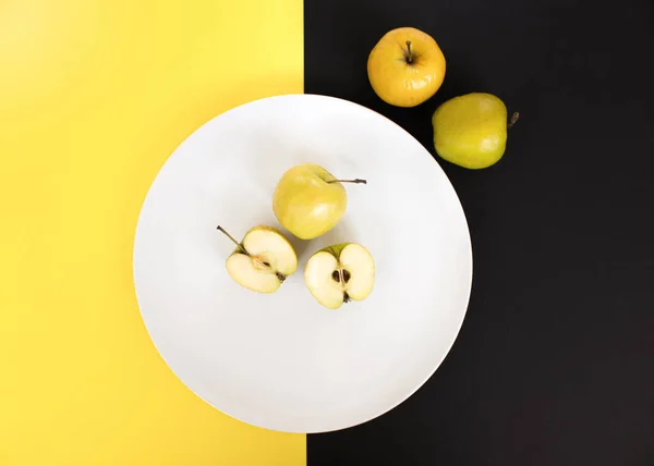 Fatias de maçã em uma placa branca em um fundo amarelo-preto, visão superior, espaço para texto — Fotografia de Stock