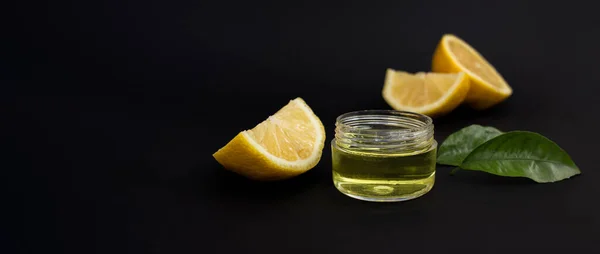 Siyah arka planda limon dilimleri ve kozmetik limon yağı. Kapat, metin için boşluk