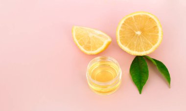Pembe arka planda limon dilimleri ve kozmetik limon yağı. Kapat, metin için boşluk