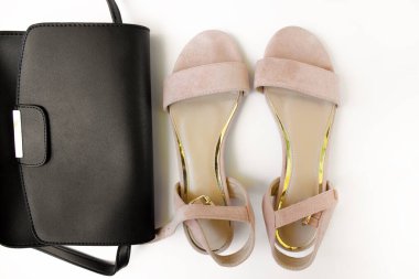 Siyah kadın çantası ve beyaz arka planda pembe sandaletler. Güzellik blogu konsepti. Kadın aksesuarları.