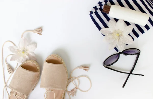 Summer Flat lay. Summer sandals, white flowers, sunglasses and a white bottle.Top view. Creative background.