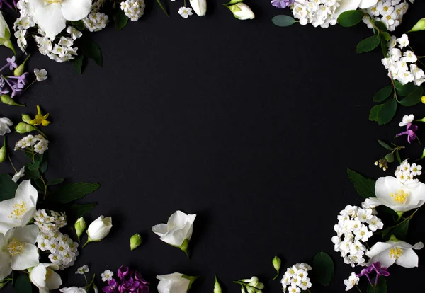 Bloemen frame gemaakt van verschillende lentebloemen op zwarte achtergrond. Bloemen plat lag. Ruimte voor tekst — Stockfoto