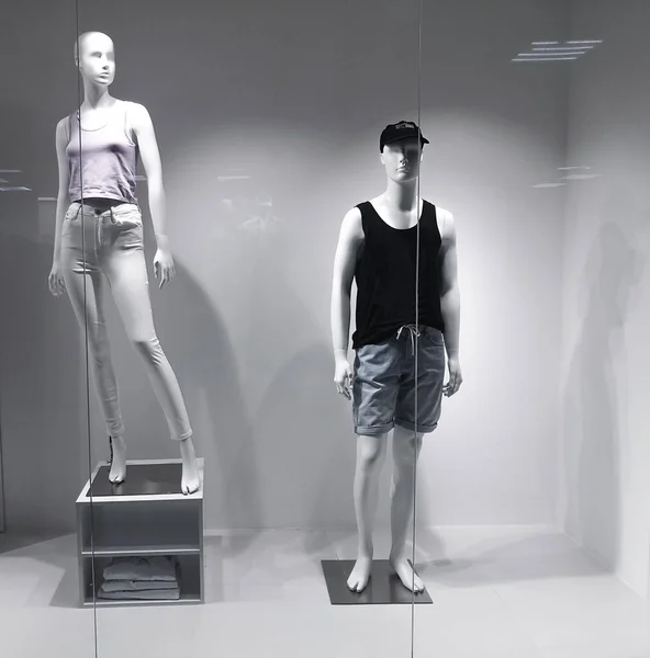 Dos maniquíes en un escaparate detrás del vidrio. Maniquíes de hombre y mujer vestidos con ropa. Tienda Manekens venta. — Foto de Stock