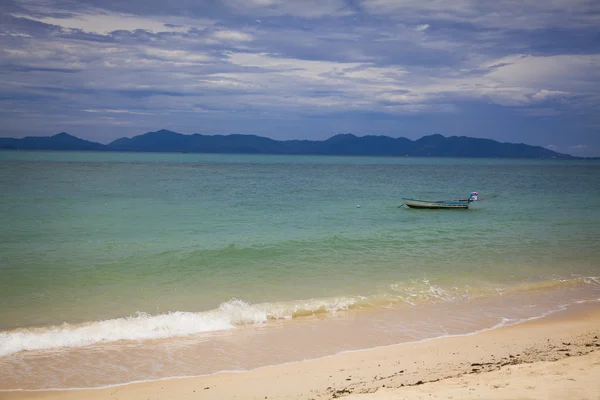 Vistas a la playa con agua azul y arena. Barco en el mar —  Fotos de Stock
