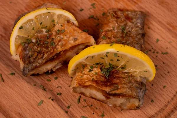 stock image two pieces of fish baked and decorated with lemon top view