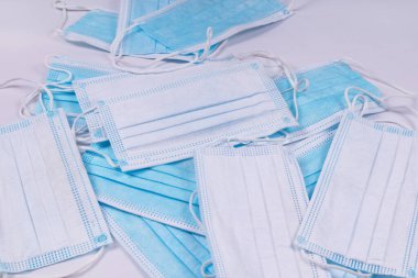 Bir yığının içinde tıbbi maskeler var, bazıları beyaz, bazıları mavi.