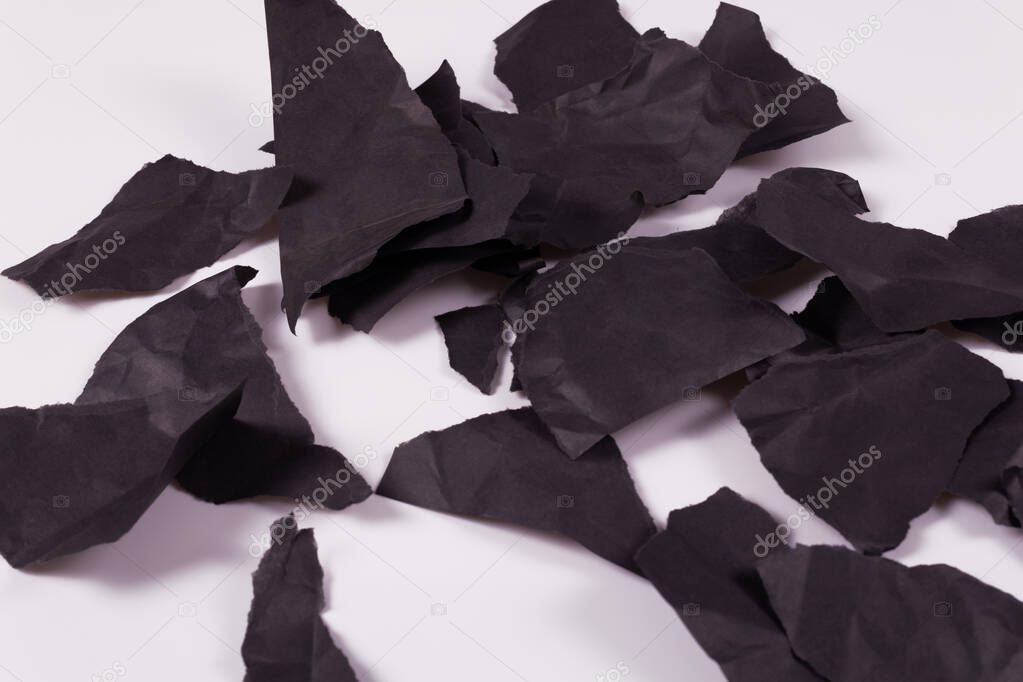 many pieces of black crumpled paper lying on a white surface