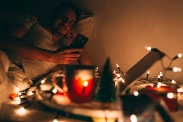 Yoiung adamı Noel arifesinde evinde takılıyor, cep telefonunu kullanıyor. Güzel sıcak ortam, 