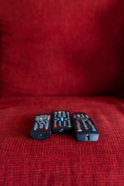 Ağaç TV uzaktan kumandaları kırmızı koltukta birbirine bağlanmış.