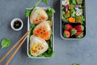 Izgara Onigiri Bento ve beslenme çantalarında yumurta ve yemek çubuklarıyla çilek, işe giderken lezzetli ve sağlıklı yemekleri götürme kavramı, ev yapımı Japon mutfağı. 