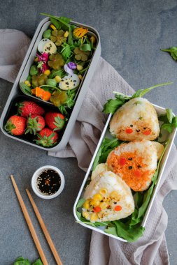 Izgara Onigiri Bento ve beslenme çantalarında yumurta ve yemek çubuklarıyla çilek, işe giderken lezzetli ve sağlıklı yemekleri götürme kavramı, ev yapımı Japon mutfağı. 