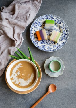 Tabaklar buğday lapası ve hindistan cevizi sütü ile masada nyonya kueh, Malezya Nyonya tatlı lezzeti 