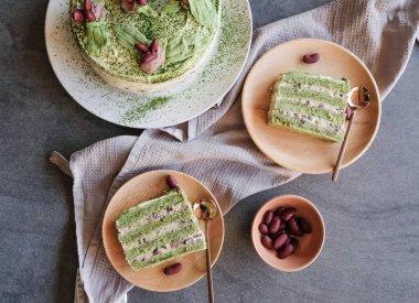 Büyük kırmızı fasulyelerle süslenmiş ev yapımı kibritli kek. El yapımı yeşil çay yaprakları ve tabakta dilimler.