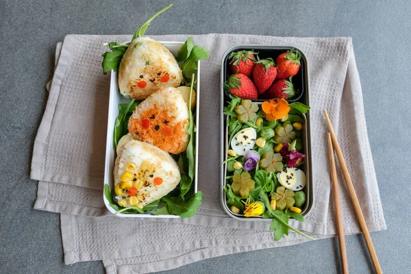 Izgara Onigiri Bento ve beslenme çantalarında yumurta ve yemek çubuklarıyla çilek, işe giderken lezzetli ve sağlıklı yemekleri götürme kavramı, ev yapımı Japon mutfağı. 