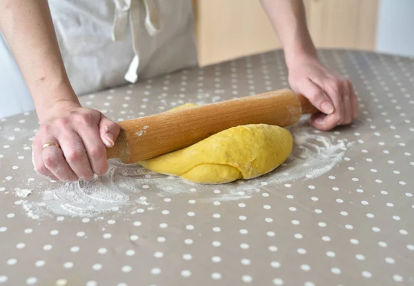 Hands baking dough with rolling pin on the table