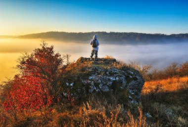 Dağlarda yürüyüş yapan bir kadın kayalıklarda yürüyor. Renkli sonbahar gündoğumu