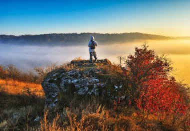 Dağlarda yürüyüş yapan bir kadın kayalıklarda yürüyor. Renkli sonbahar gündoğumu