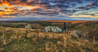 Dağlarda yürüyüş yapan bir kadın kayalıklarda yürüyor. Renkli sonbahar gündoğumu