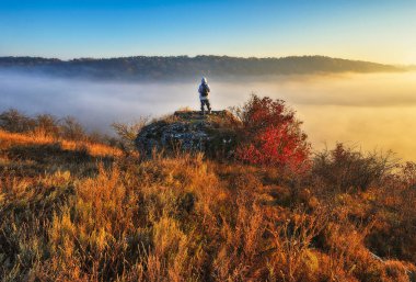 Dağlarda yürüyüş yapan bir kadın kayalıklarda yürüyor. Renkli sonbahar gündoğumu