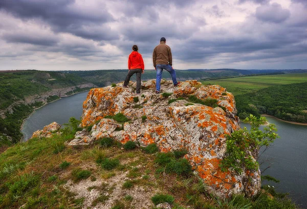 couple of tourists on the rock. a man and a woman look at the picturesque river canyon