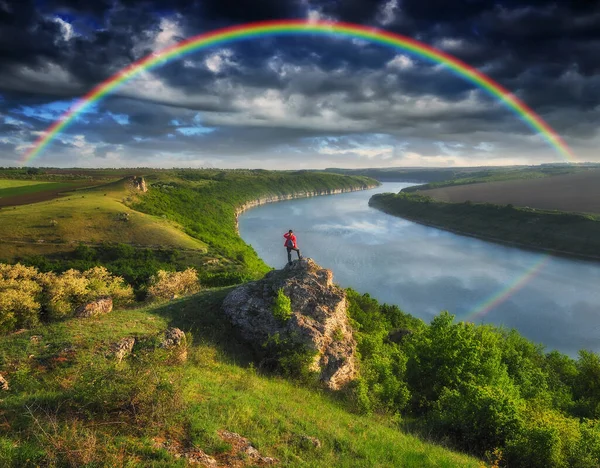 虹が川を渡って 渓谷の上の崖の上の女性は — ストック写真