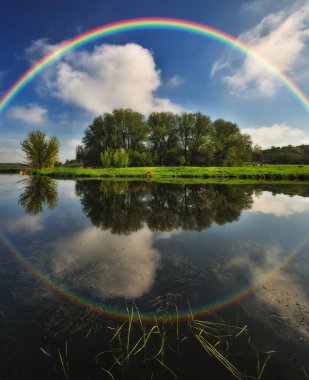 Baharda nehirde gökkuşağı olan bir manzara. Renkli bir sabah