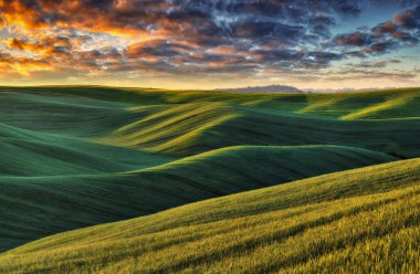 Tepeli bir tarlanın üzerindeki resimsel bulutlar. Kırsal alanda çarpıcı bir gökyüzü