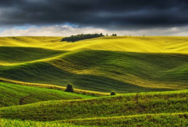 Tepeli bir tarlanın üzerindeki resimsel bulutlar. Kırsal alanda çarpıcı bir gökyüzü