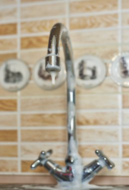 Temizlik köpüğüyle kaplı pis bir mutfak musluğunun yakın çekimi.