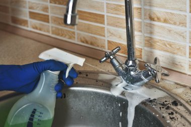 Temizlik köpüğüyle kaplı pis bir mutfak musluğunun yakın çekimi.