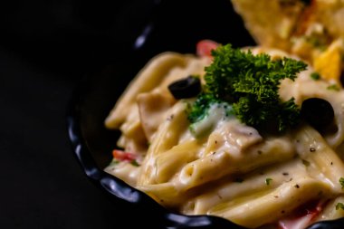 Lezzetli, siyah kasede beyaz soslu makarna..