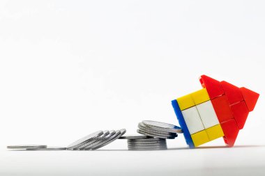 Beyaz arka planda para ve bozuk paralarla çekilmiş lego evi oyuncağı.