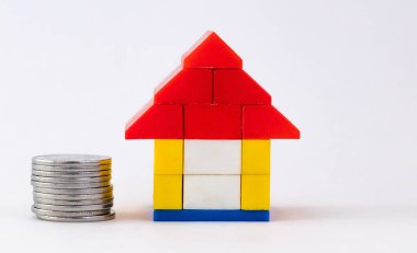  Ev kredisi ve sigorta konseptinde birikmiş lego evi ve madeni paraların yakın çekimi.