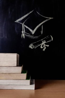 Bir Kare Akademik veya Mezuniyet şapkasının merdiven basamakları şeklinde düzenlenmiş kitap yığınıyla portre modu görüntüsü - İlerleme kavramı