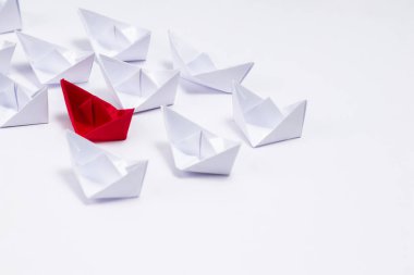 Yüksek açılı, kırmızı bir teknenin beyaz kağıt teknelerin arasına yakın çekim yaparak donanma gücü kavramını gösteriyor.